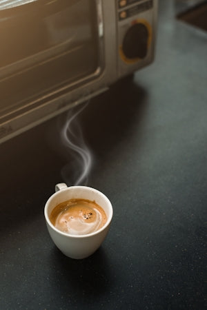 a cup of coffee sitting in front of a toaster oven